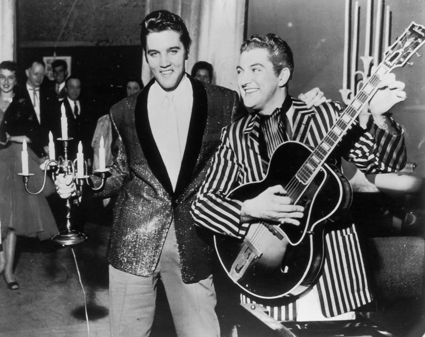 Elvis Presley holding a candelabra and Liberace playing guitar, trading places in Las Vegas, 1956
